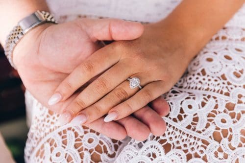 A person hand wearing a diamond engagement ring