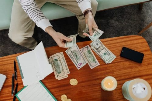 Person organizing cash with budget notes to plan expenses and work toward financial goals