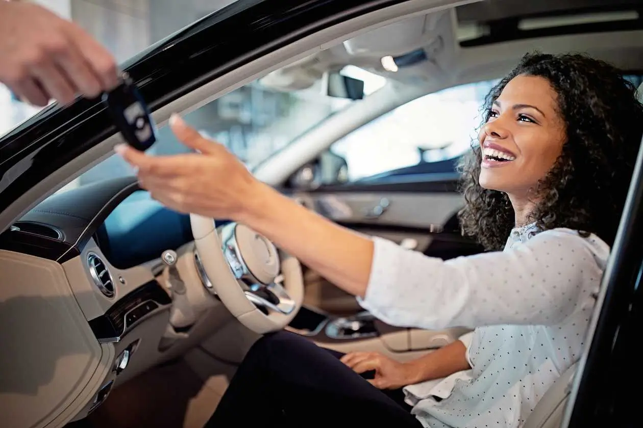 a woman sitting in a rental car smiling