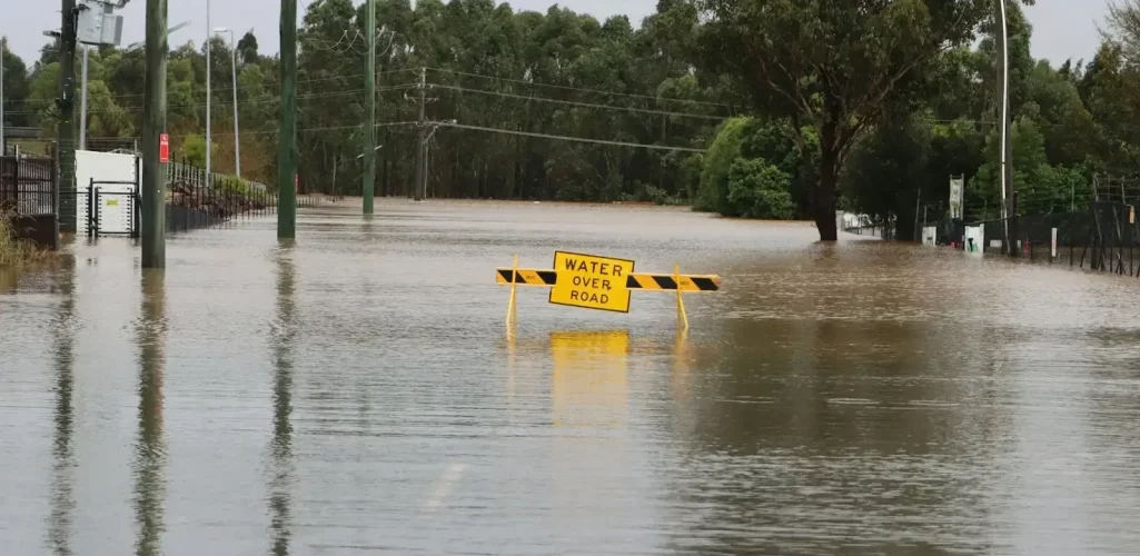 a flooded road with a yellow sign