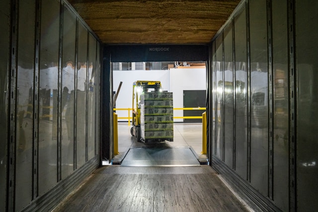 Inside A Box Truck Facing A Warehouse And A Forklift Driver